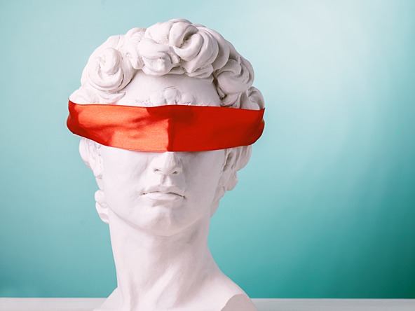 White statue blindfolded by red ribbon